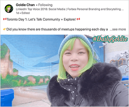 Ez egy olyan LinkedIn videó képernyőképe, amelyben Goldie Chan dokumentálja utazásait. A videó fölötti szöveg szerint „Toronto 1. napja: Beszéljünk a közösségről + fedezzük fel! Tudta, hogy naponta több ezer találkozó történik a... többet látni". A videón Goldie látható egy falfestmény előtt egy téglafalon. A falfestményen ragyogó kék ég és barna sziklák láthatók, amelyeket élénk zöld borítja. Goldie megjelenik a mellkasától felfelé. Zöld hajú ázsiai nő. Kék kötött sapkát és szőrös gallérú fekete parkot visel. A videó jobb felső sarkában a #DailyGoldie őszibarack szövegben, zöld körvonallal jelenik meg.