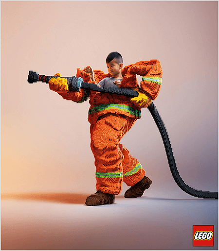 Ez egy fotó egy LEGO-hirdetésből, amelyen egy fiatal ázsiai fiú látható, amely egy LEGO-ból készült tűzoltó egyenruhában van. Az egyenruha narancssárga, neonzöld csíkkal a kabát és a nadrág mandzsettája körül. A tűzoltó egyik lábával háttal áll, és egy szintén legókból készült tűzrakót tart. A fiú feje megjelenik az egyenruha felső részén, amely sokkal nagyobb, mint ő, és a váll körül megáll. A fénykép sima semleges háttérrel készült. A LEGO logó egy piros mezőben jelenik meg a jobb alsó sarokban. Talia Wolf szerint a LEGO remek példa egy márkára, amely érzelmeket használ a reklámozásban.